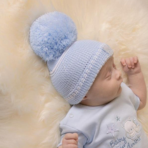 Sleeping baby on cream fur blanket wearing first size embroidered teddy hat - blue